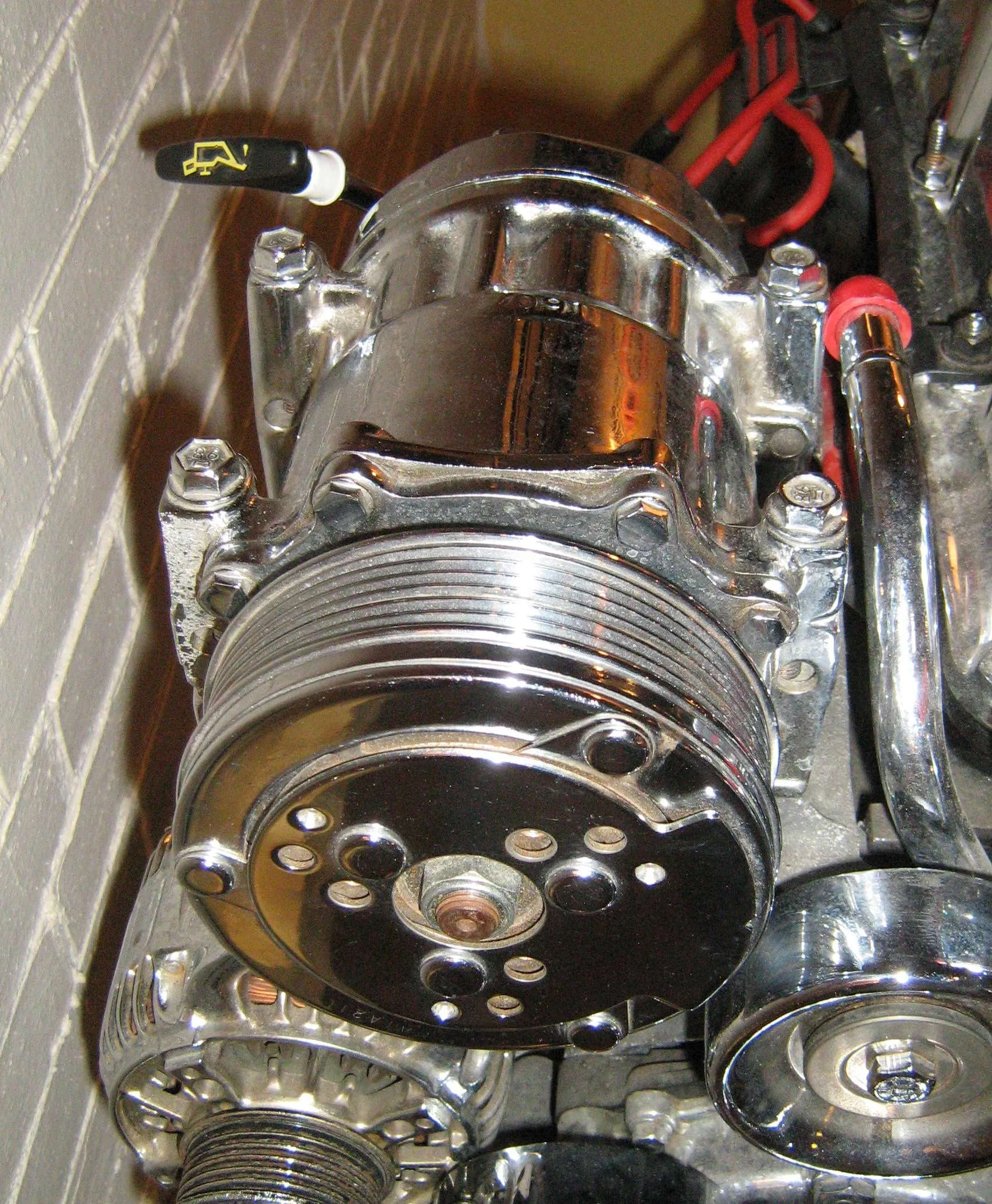 Chromed Jeep 2.5 display engine, close-up of the air-conditioning compressor from the front, grooved clutch pulley in the belt