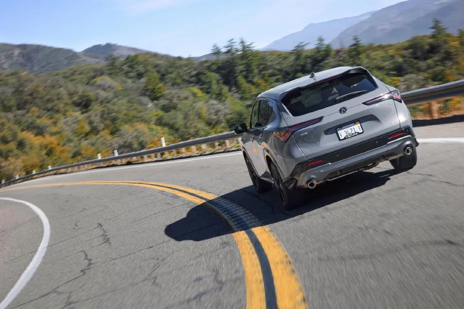 Gray 2026 Acura ADX A-Spec, front three-quarter on a mountain road with a Diamond Pentagon grille and wide-set LED DRLs