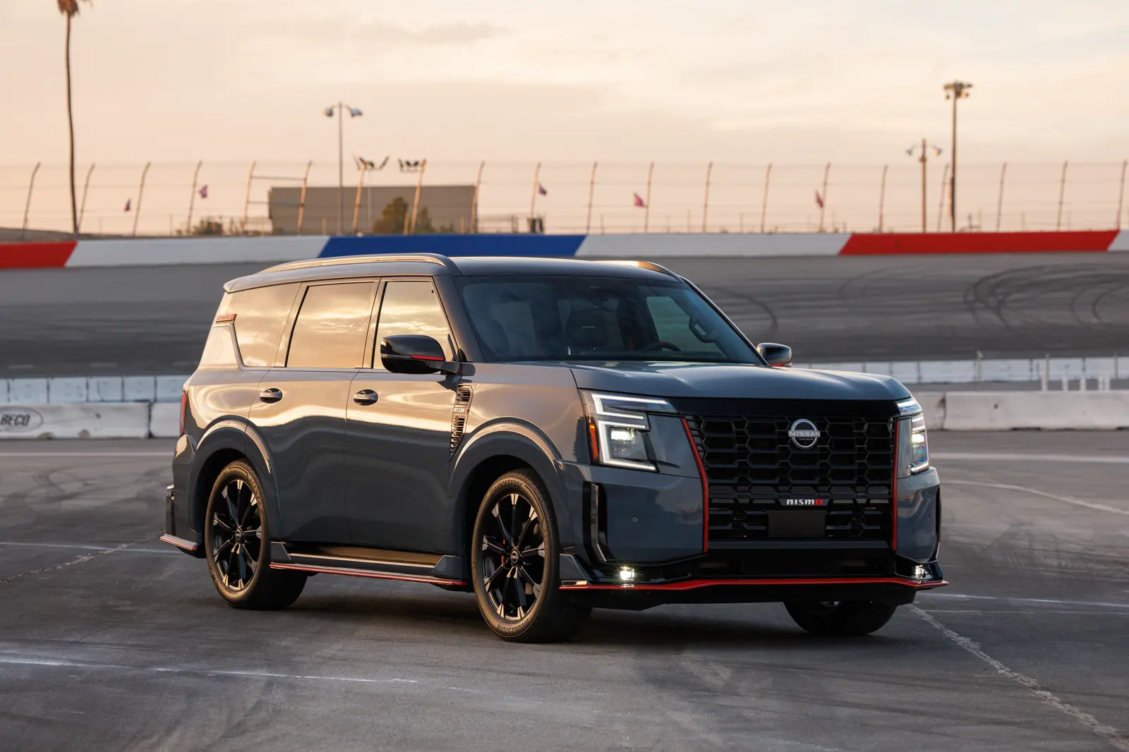 Stealth Gray 2026 Nissan Armada NISMO, front three-quarter on a racetrack with a tall V-motion mesh grille