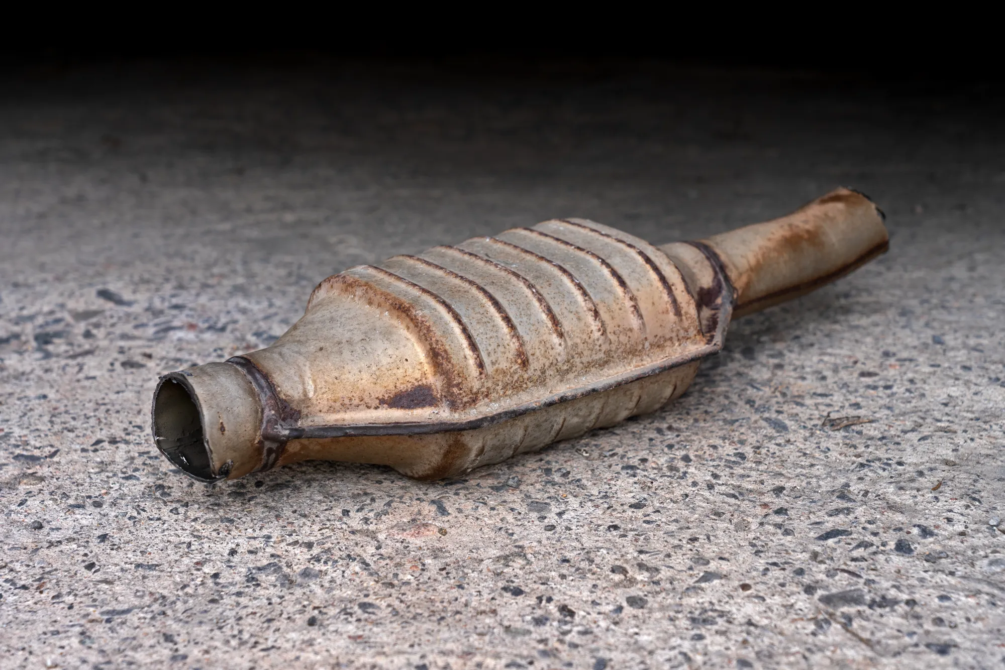 Used catalytic converter can on the ground, oval steel shell and cut pipes