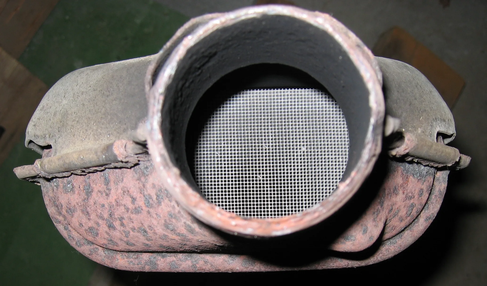 Looking into a rusty catalytic converter, ceramic honeycomb brick filling the inlet