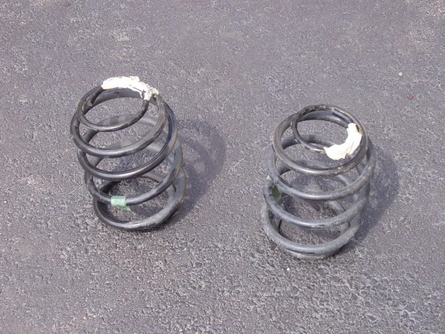 Rear suspension of a 2005 Jeep Liberty with the wheel off: coil springs between the solid axle and the frame, differential in the axle, and a shock absorber beside the springs