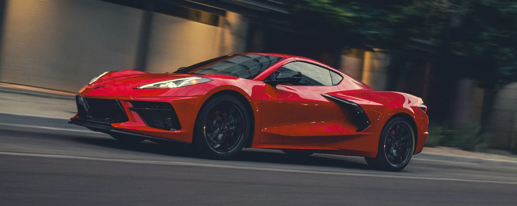 Red 2026 Chevrolet Corvette Stingray, low front three-quarter in motion with a short nose and swept lamps