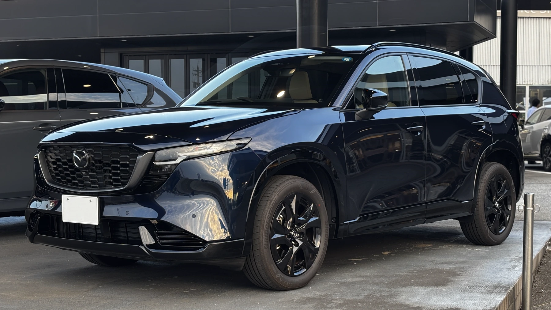 Side view of a third-generation Mazda CX-5 with silver roof rails, body-color wheel arches, and dark lower body cladding