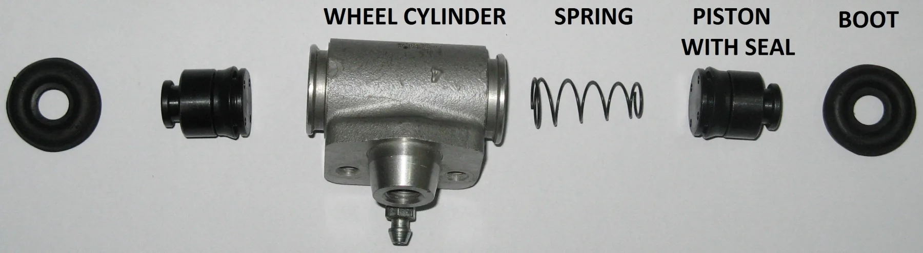 Parts in one row on a light gray background, each with black capital letters printed on the photo. From left to right: a black rubber boot, a piston with seal, the gray cast WHEEL CYLINDER body (open bores at both ends, a threaded inlet boss underneath, and a bleeder screw), a SPRING, a PISTON WITH SEAL, and a BOOT. There are no metal clips and no separate small seals.