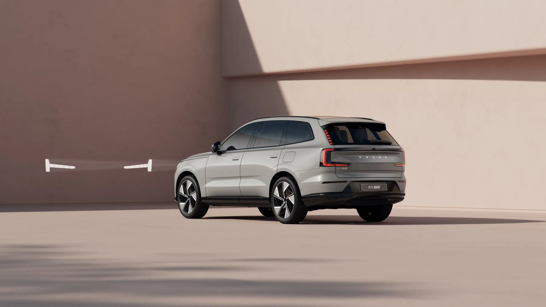 Silver 2026 Volvo EX90, studio rear three-quarter with vertical tail lamps climbing the glass