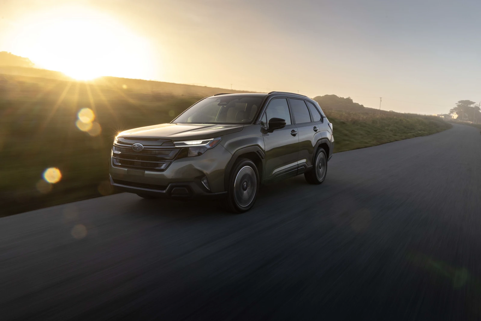 Green 2026 Subaru Forester Hybrid, front three-quarter on a coastal road with a tall hexagonal grille and C-shaped lamps