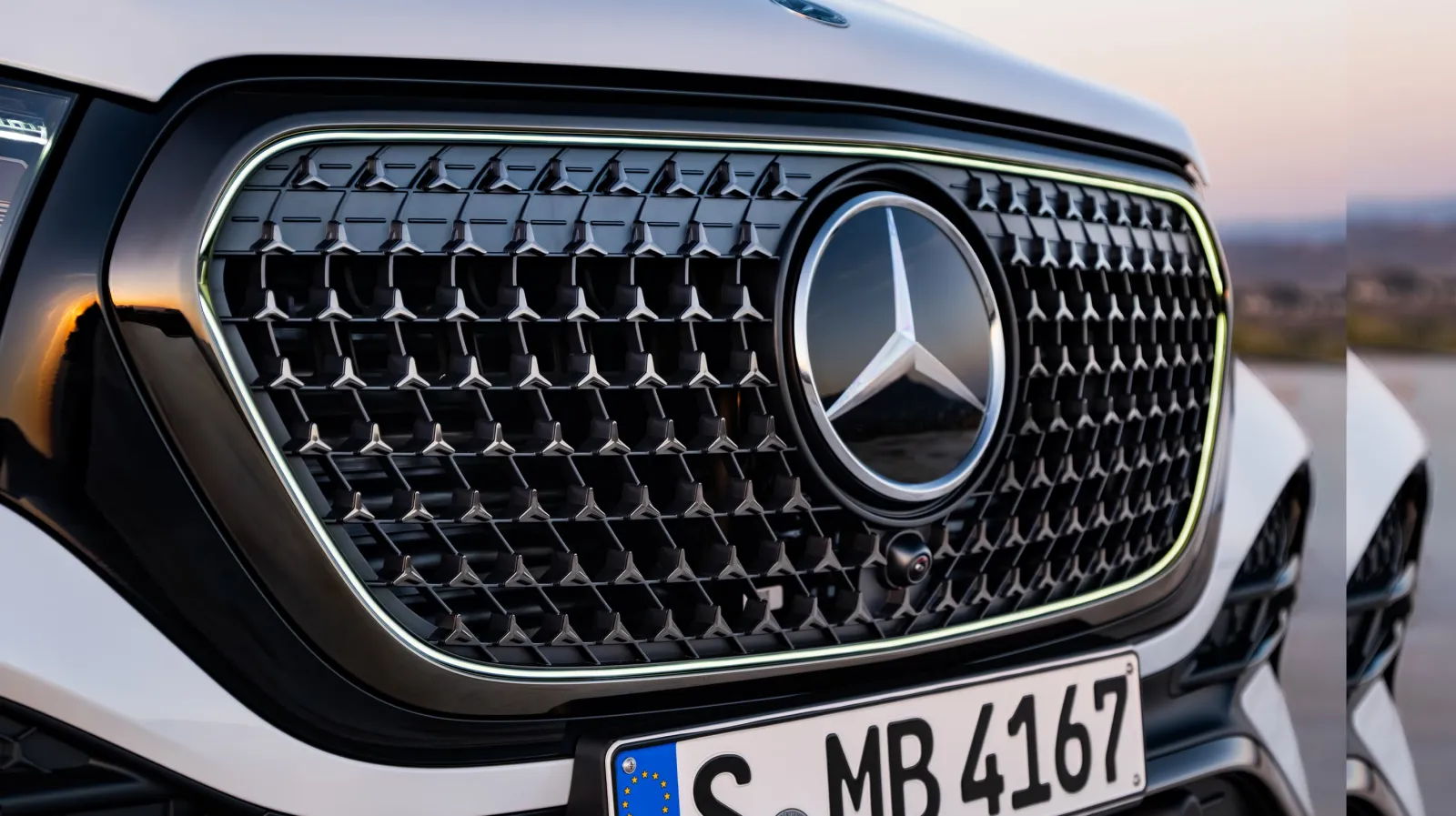 2027 Mercedes-Benz GLE grille close-up with an illuminated central star, contour lighting, and star-pattern mesh