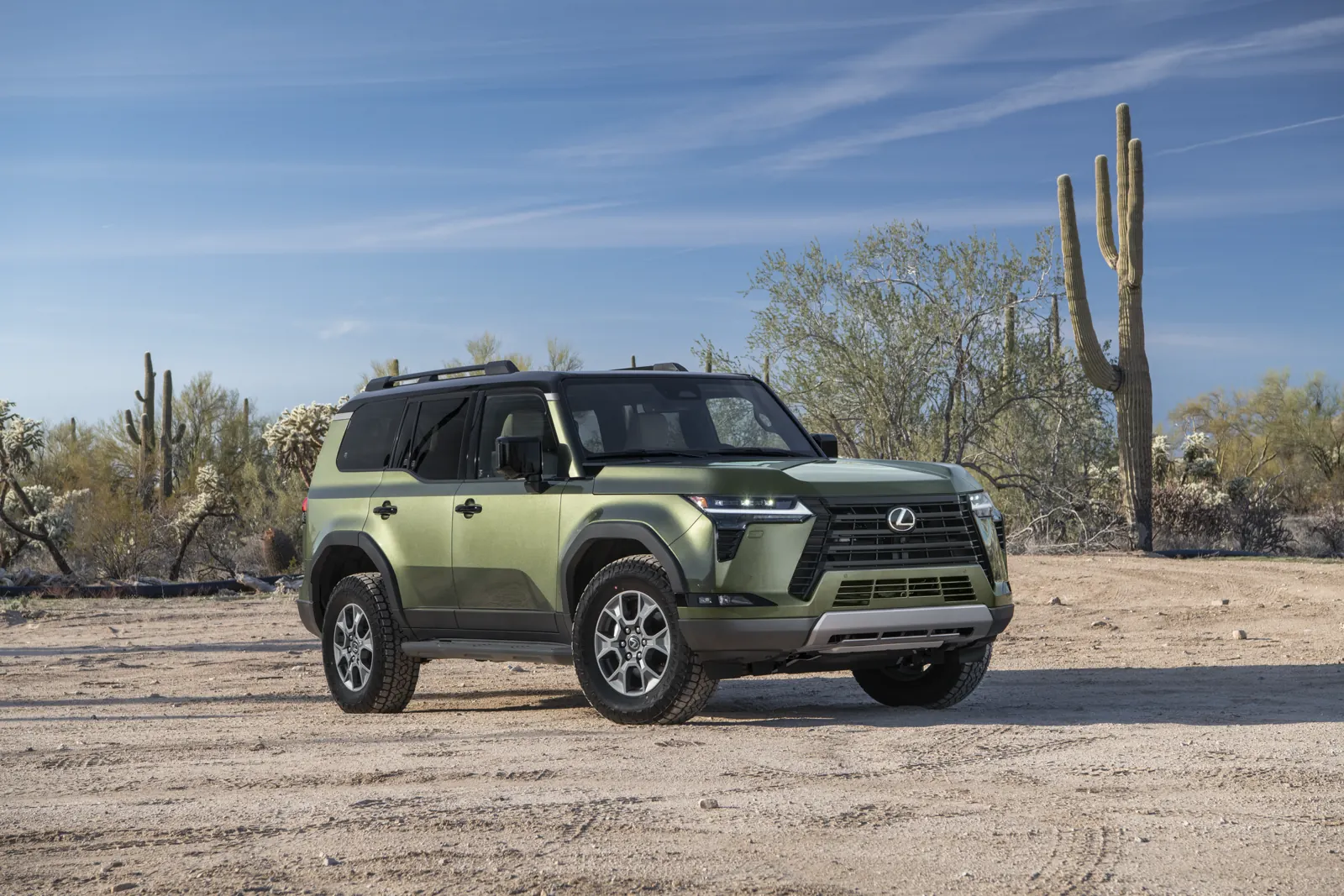 Nori Green 2026 Lexus GX Overtrail+, front three-quarter on desert gravel with a spindle grille and upright glass