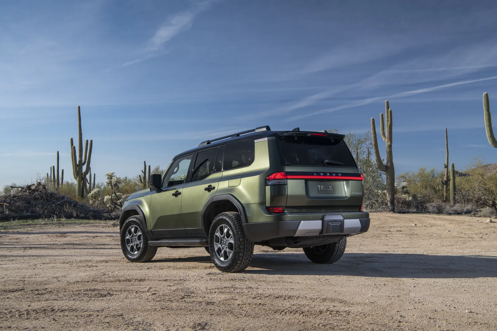 Nori Green 2026 Lexus GX Overtrail+, rear three-quarter on desert gravel with a LEXUS light bar