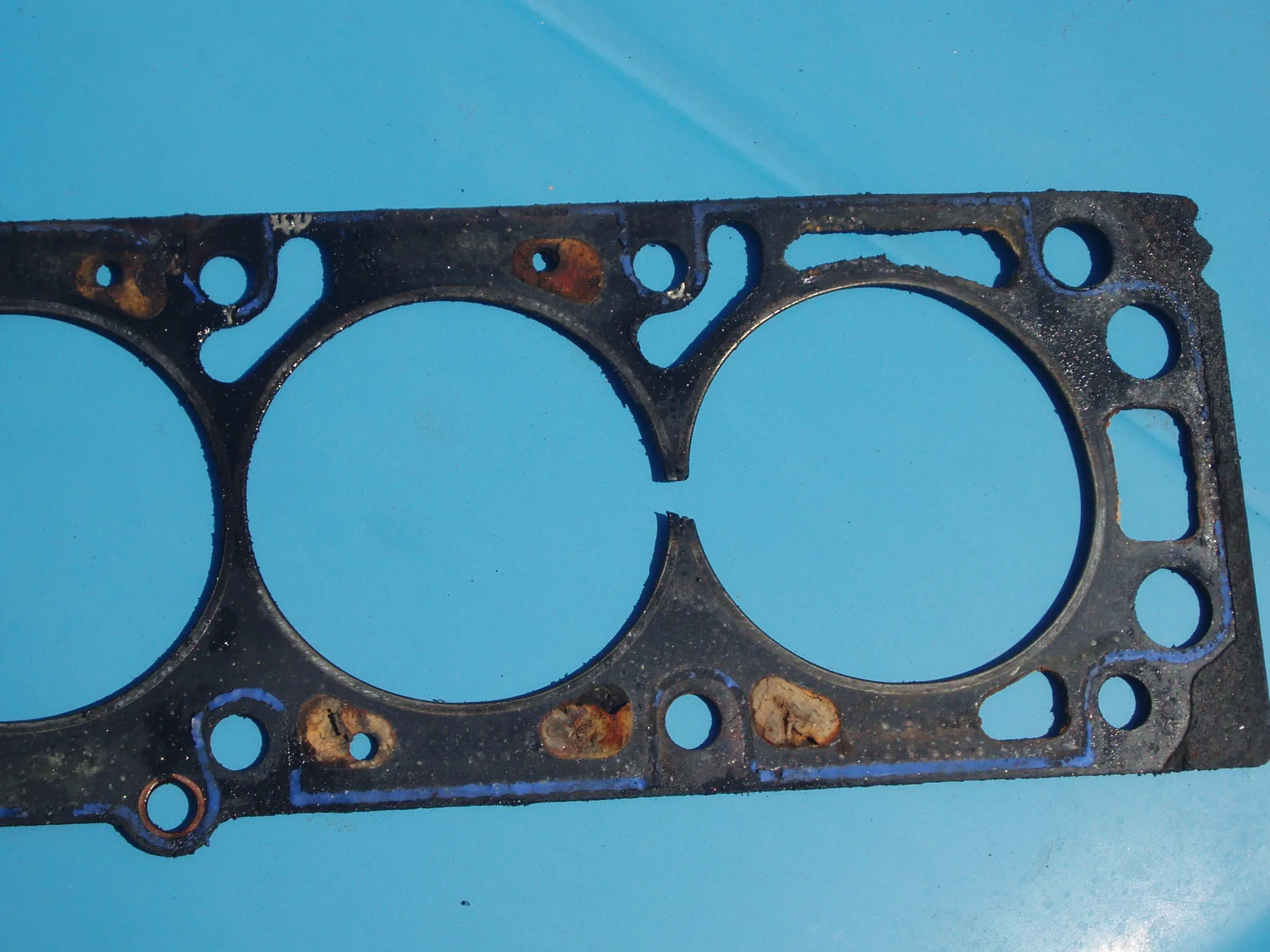Used head gasket with damage in the narrow web between adjacent cylinder openings