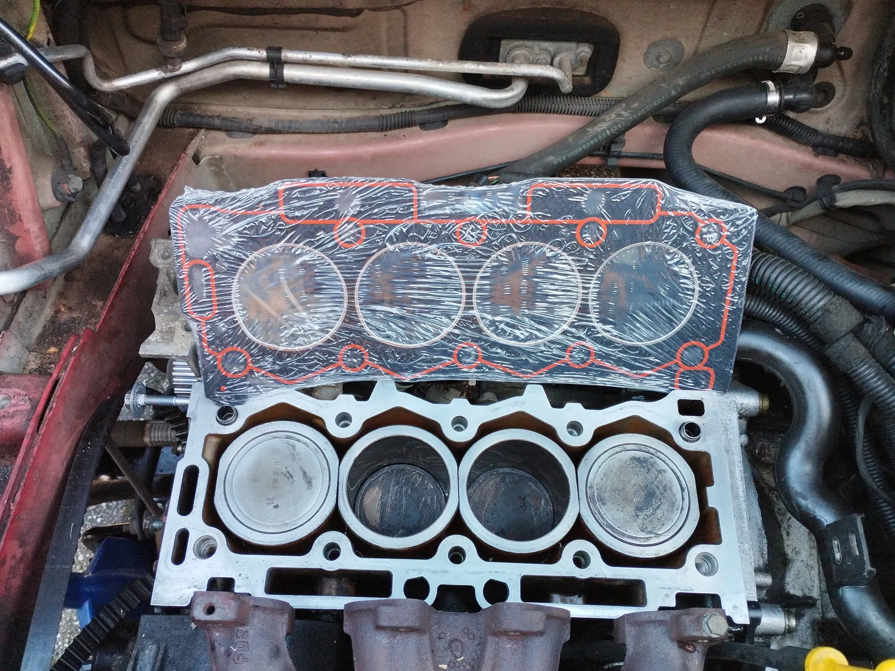 Cylinder block with the head removed and a head gasket held above the deck