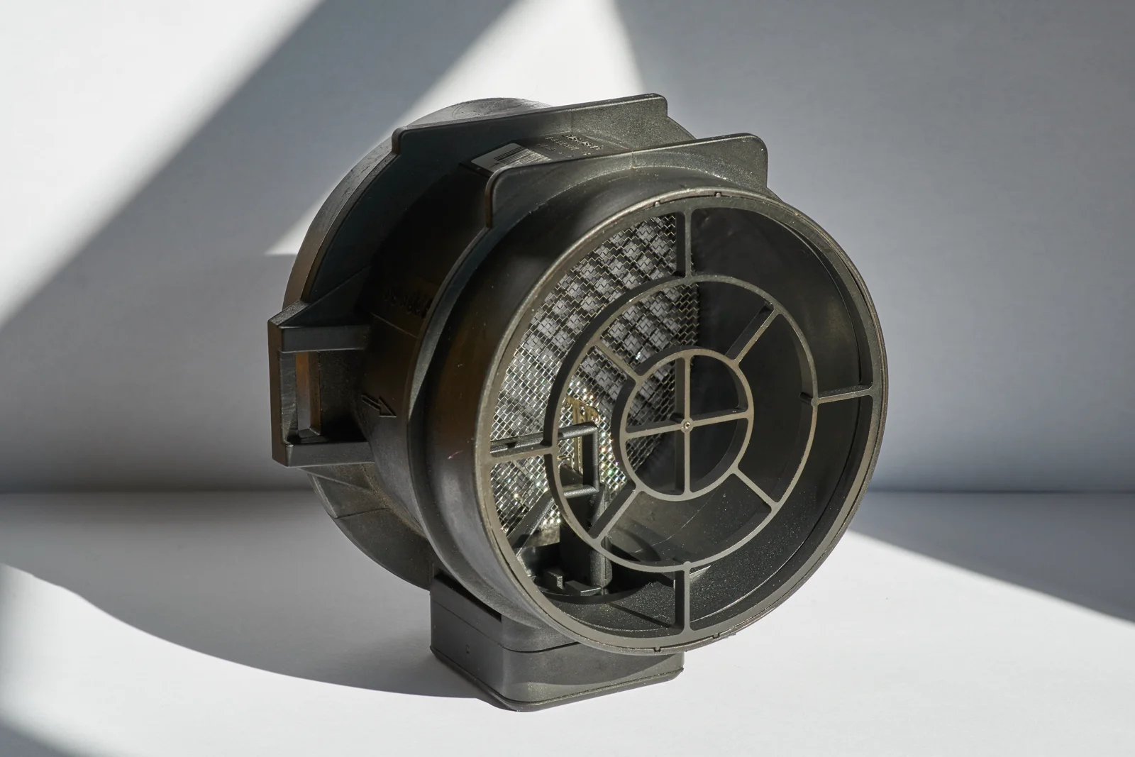 Black hot-film mass airflow sensor housing with a mesh inlet and a connector on the base