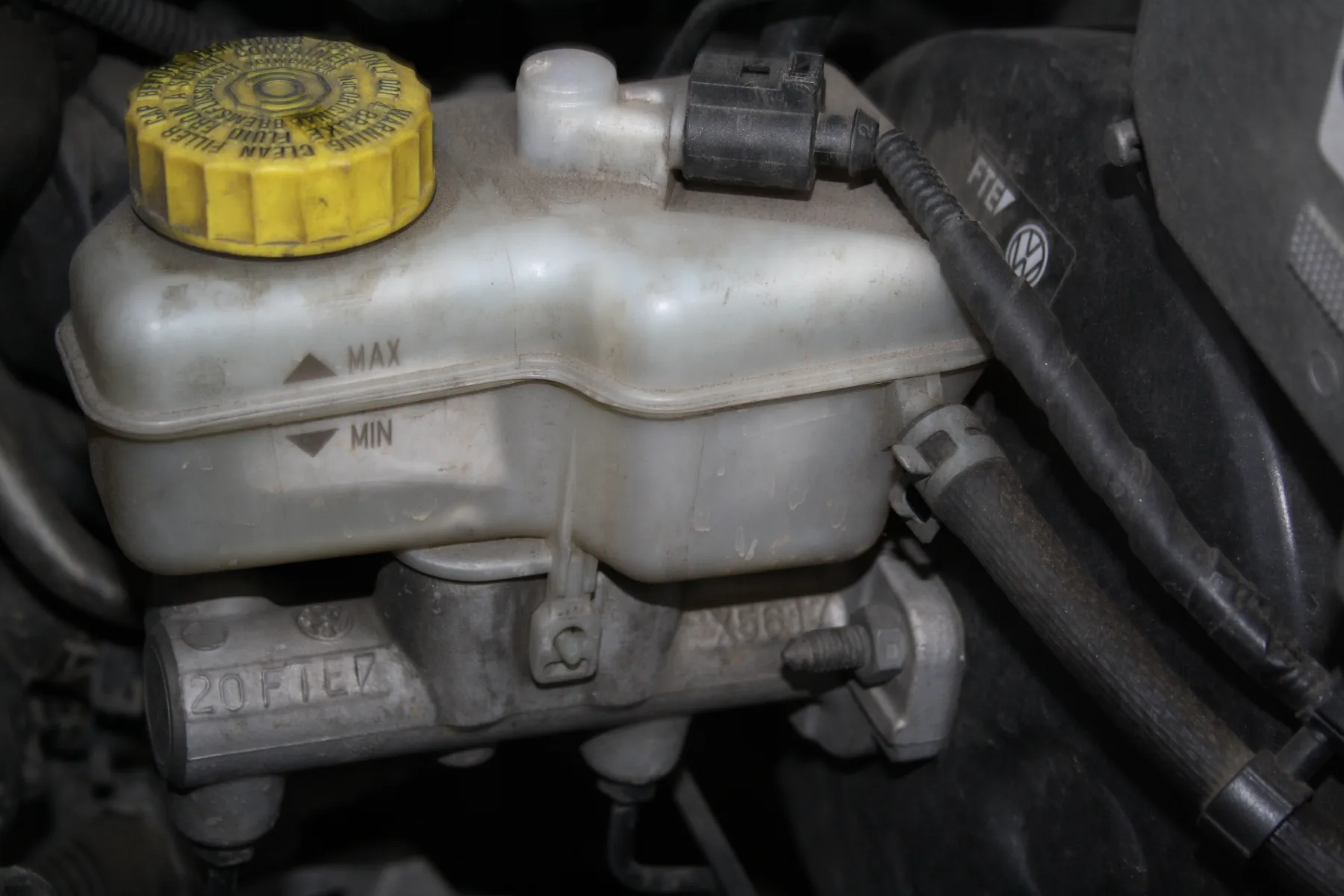Translucent brake fluid reservoir with level marks, sitting on the master cylinder in a Škoda Fabia engine bay