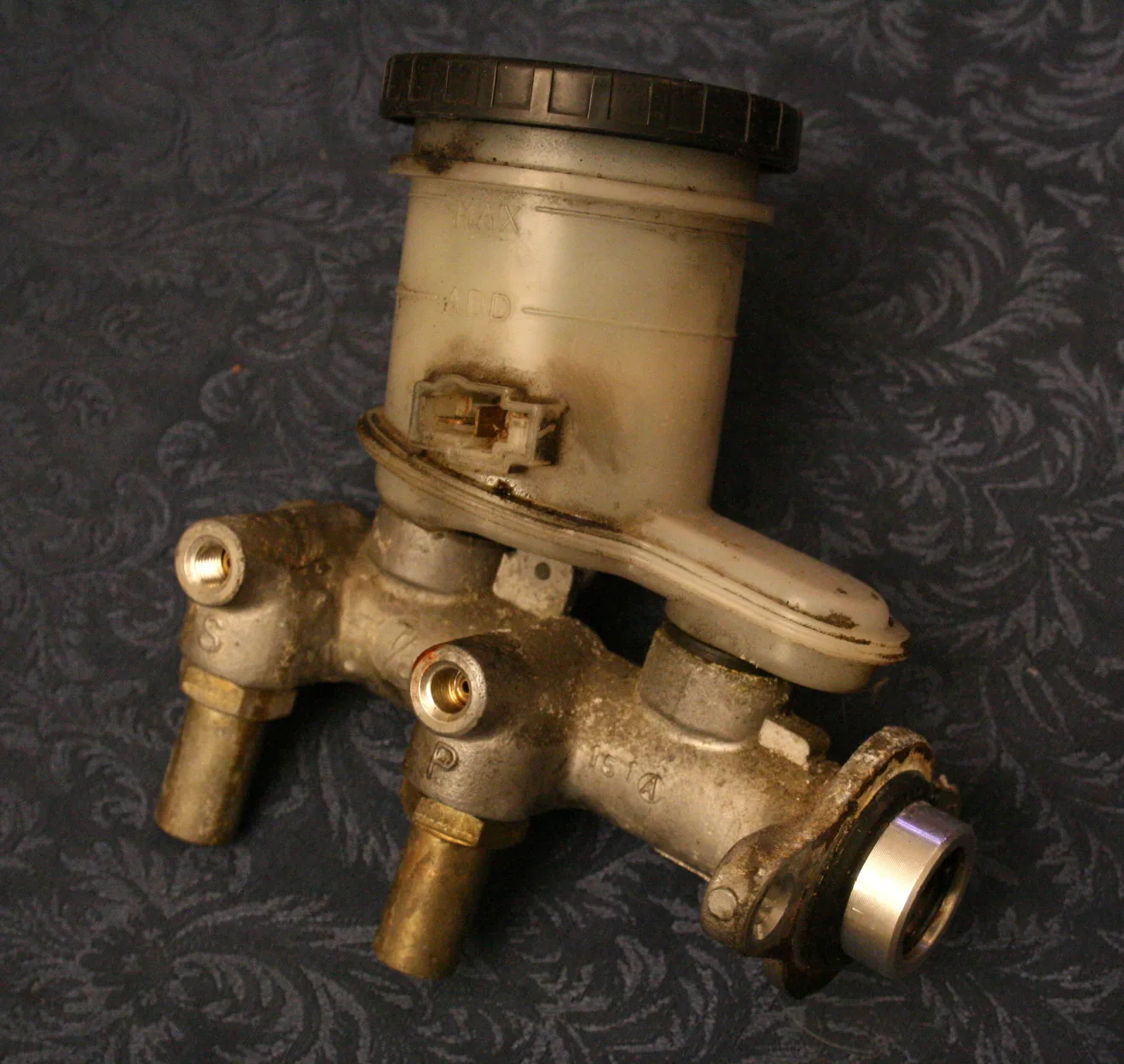 Brake master cylinder and reservoir in the engine bay of a 1990 Geo Storm GSi, beside the black vacuum booster