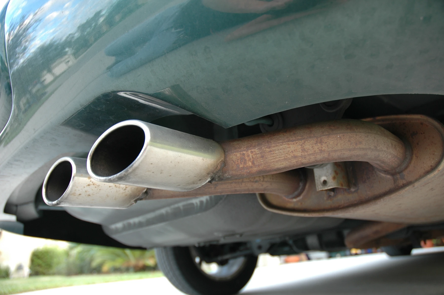 Muffler and tailpipe under a 1997 Chrysler Sebring, the oval can ahead of the pipe that exits the rear bumper