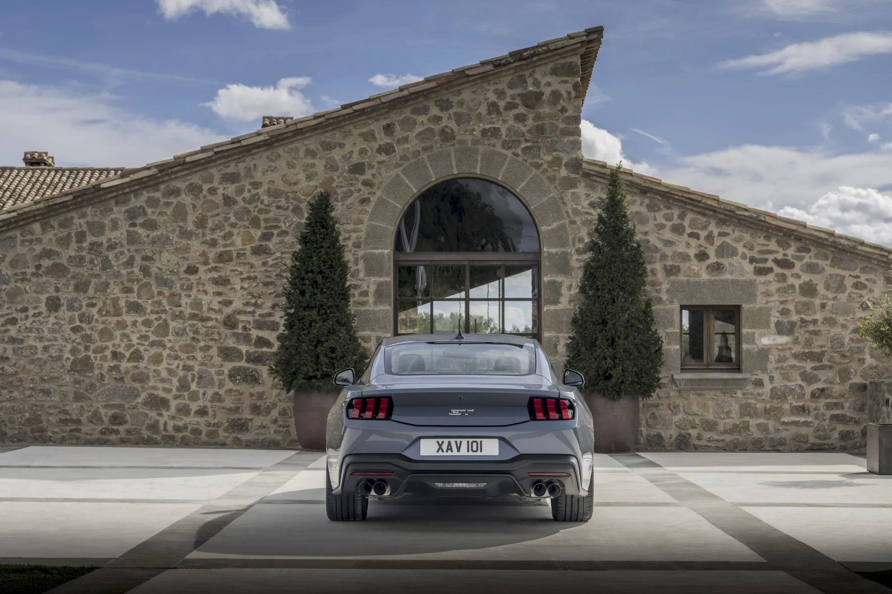 Slate 2026 Ford Mustang GT Fastback, rear with tri-bar tail lamps, GT badge, and quad exhaust tips