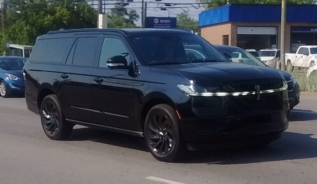 Front three-quarter of a black 2025 Lincoln Navigator L, showing the nose, a roof rail, a running board, and the long side