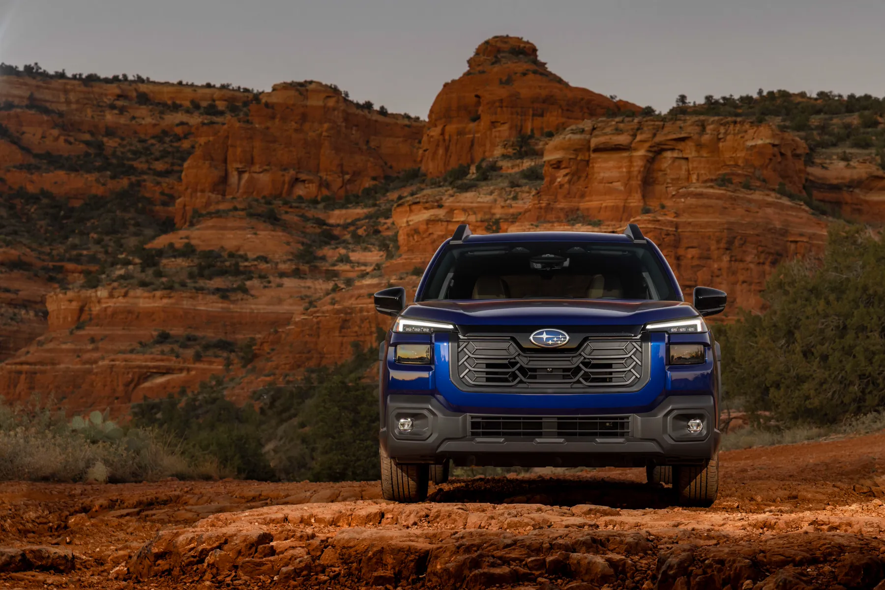 Blue 2026 Subaru Outback, straight-on nose with a tall hexagonal grille and stacked corner lamps