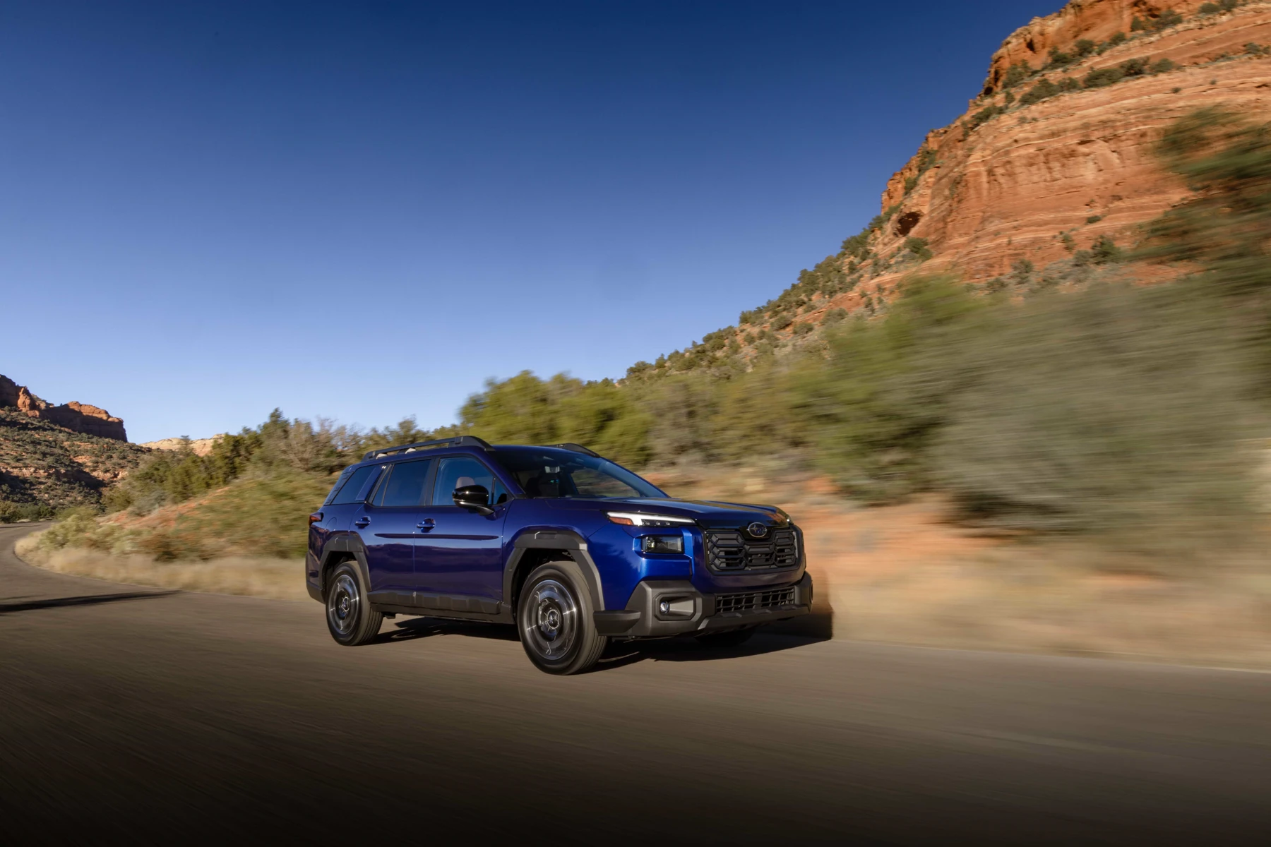 Blue 2026 Subaru Outback, front three-quarter on a desert highway