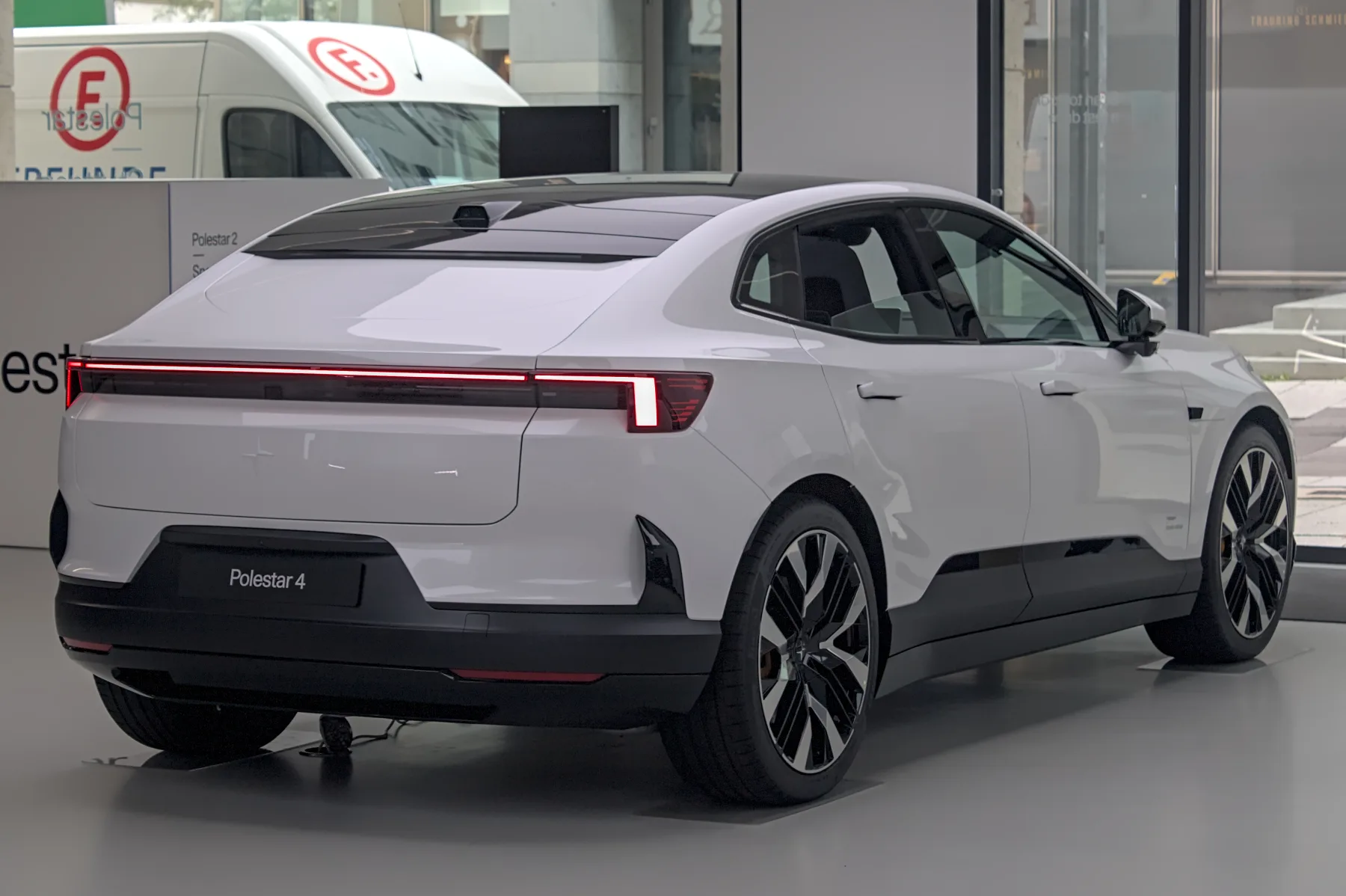 Front three-quarter of a Polestar 4 in Stuttgart, slim daytime lamp above a blank grille panel and a lower air intake
