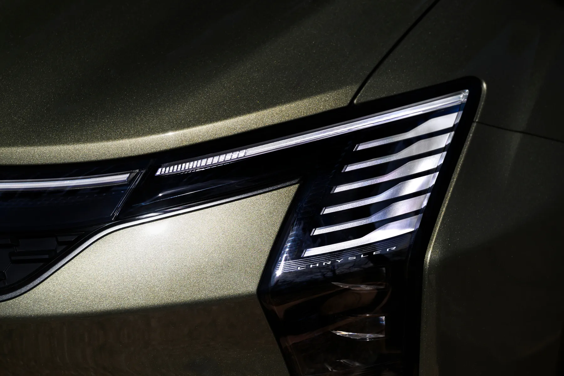Close view of a 2027 Chrysler Pacifica Limited grille, piano-key lamps lit around an illuminated wing badge