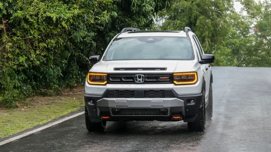 White 2026 Honda Passport TrailSport, dead-front on wet pavement with amber DRL bars, two-bar grille, and PASSPORT in the fascia