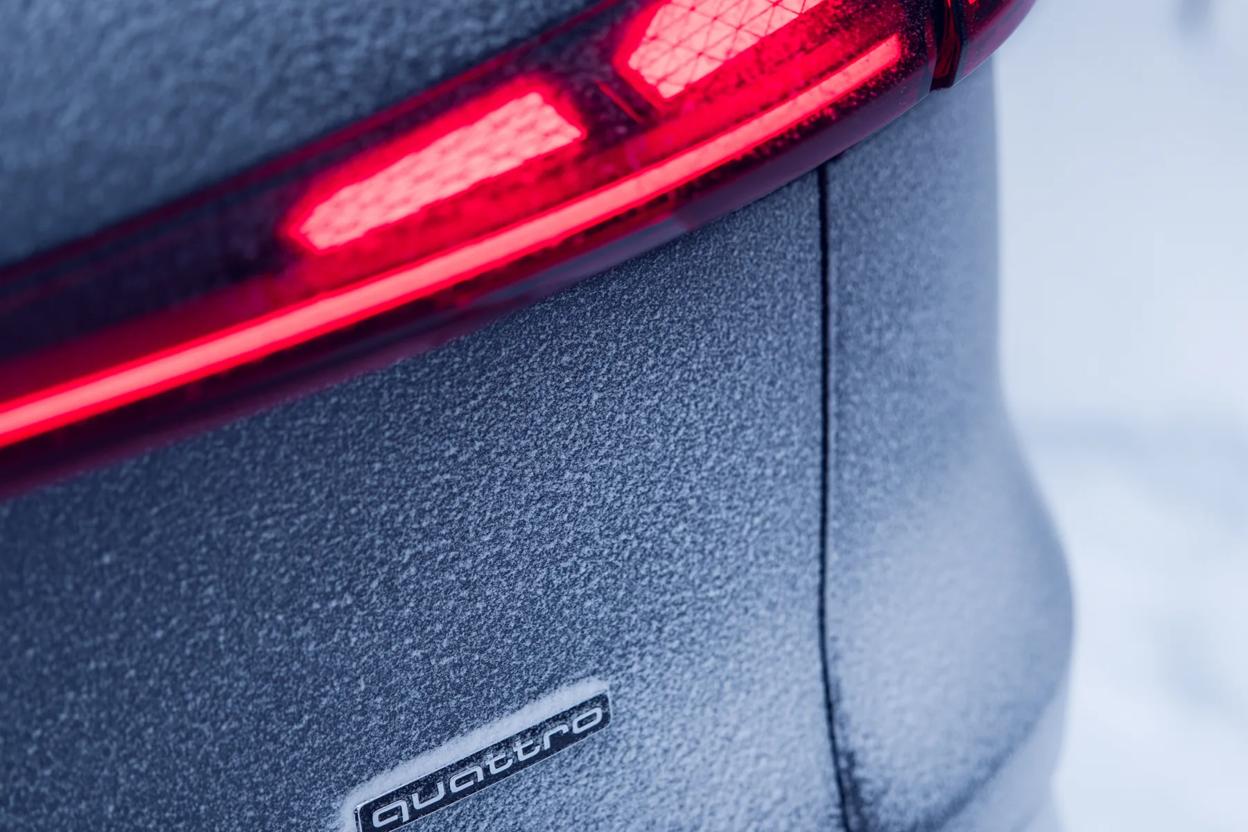 Frosted 2026 Audi Q5 tail corner with a digital red light signature, continuous LED bar, and quattro badge