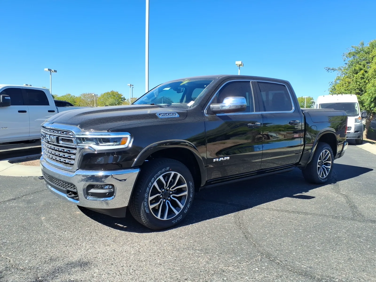 Front three-quarter of a white 2026 Ram 1500 Limited Longhorn on a dealer lot, bright grille surround, dark mesh, and chrome RAM letters in the grille