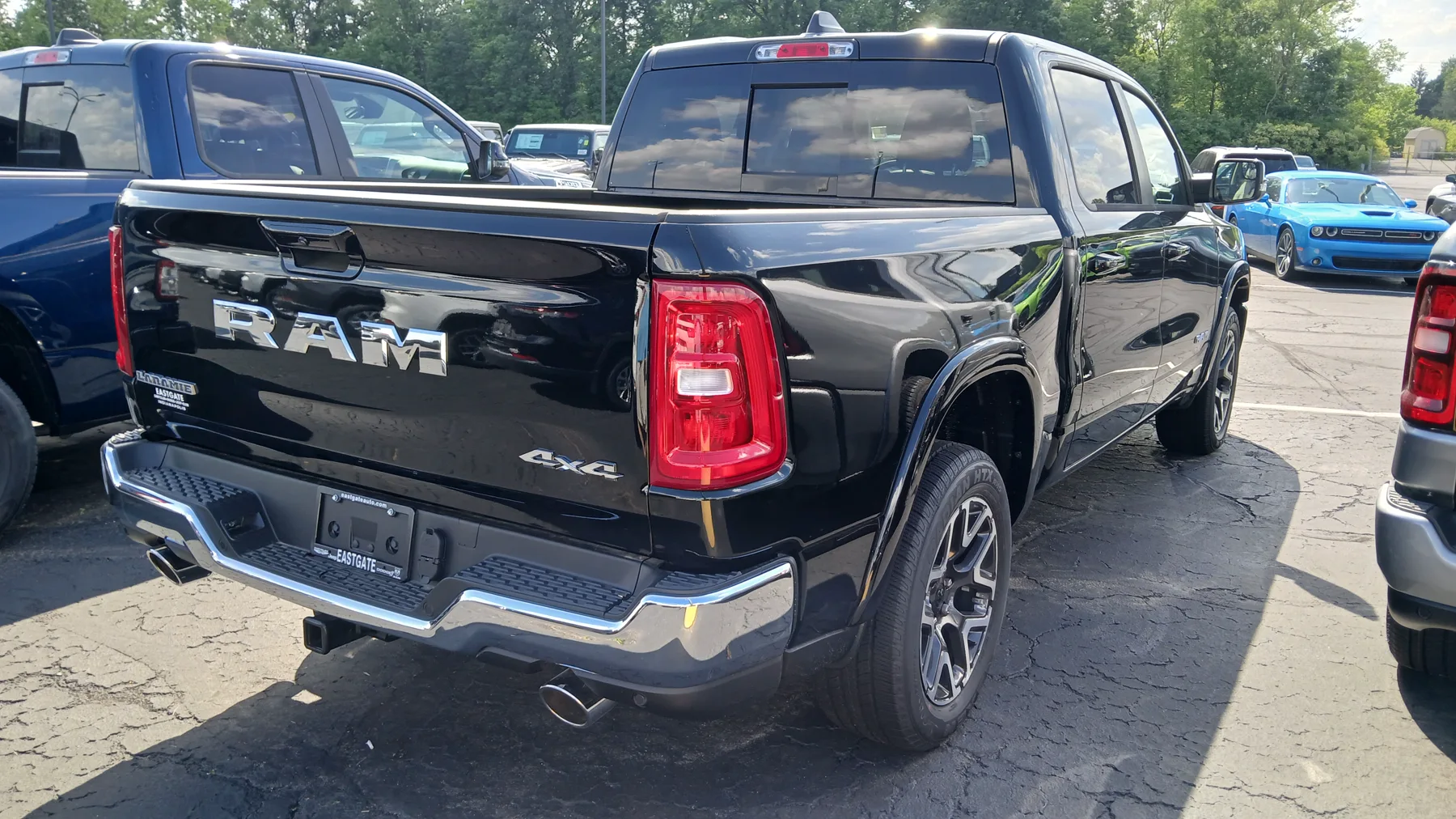 Rear of a white 2025 Ram 1500 Laramie crew cab, chrome RAM letters across the tailgate with the center brake lamp in the letter row and a Laramie badge lower on the gate