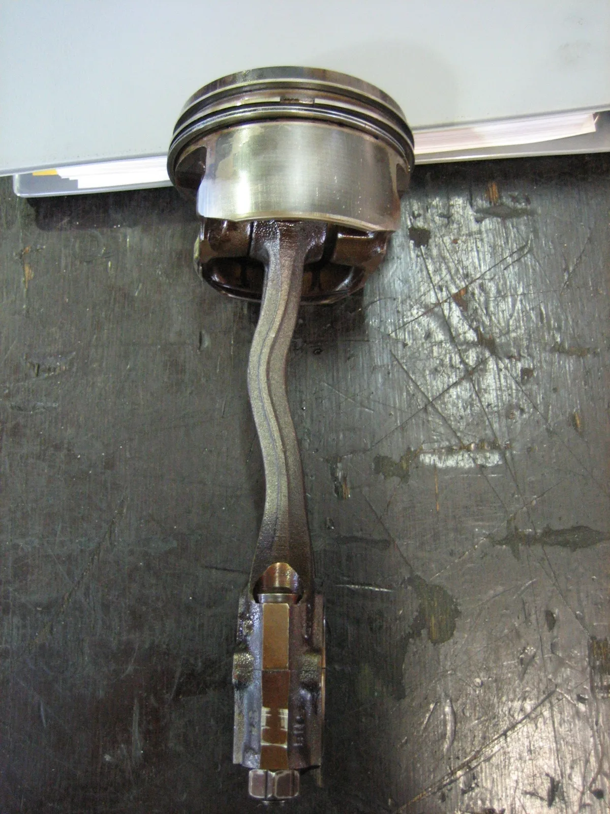 Connecting rod on a bench with a bent shank between the piston-pin eye and the big-end cap