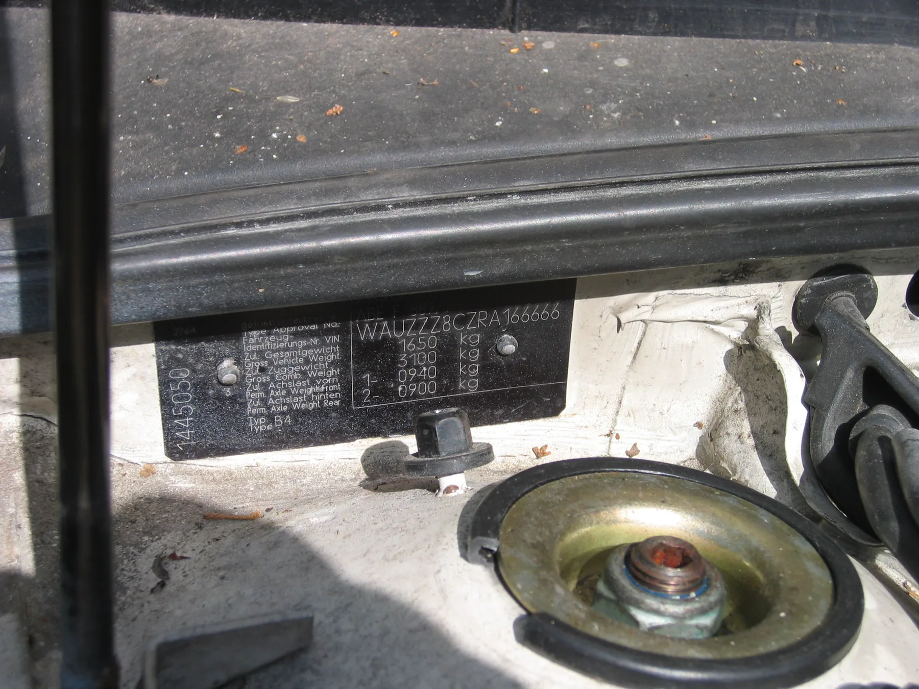 Metal identification plate by a strut tower, with a VIN line and weight ratings in kilograms