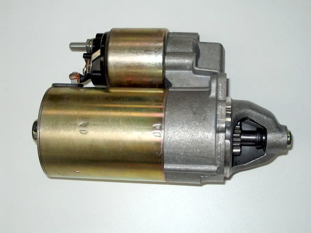Automobile starter motor with solenoid on top and pinion visible in the nose housing