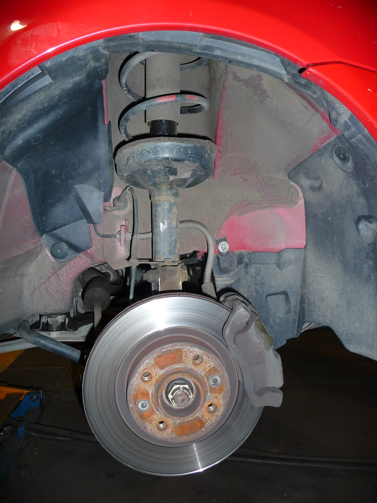 Renault front corner, wheel off: MacPherson strut tower from the inner fender down to the hub, disc, and caliper