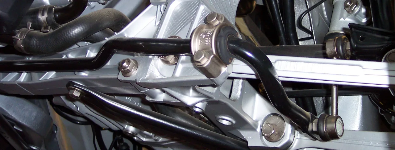 Black stabilizer bar in a split bushing on a Porsche rear subframe, drop link on the end