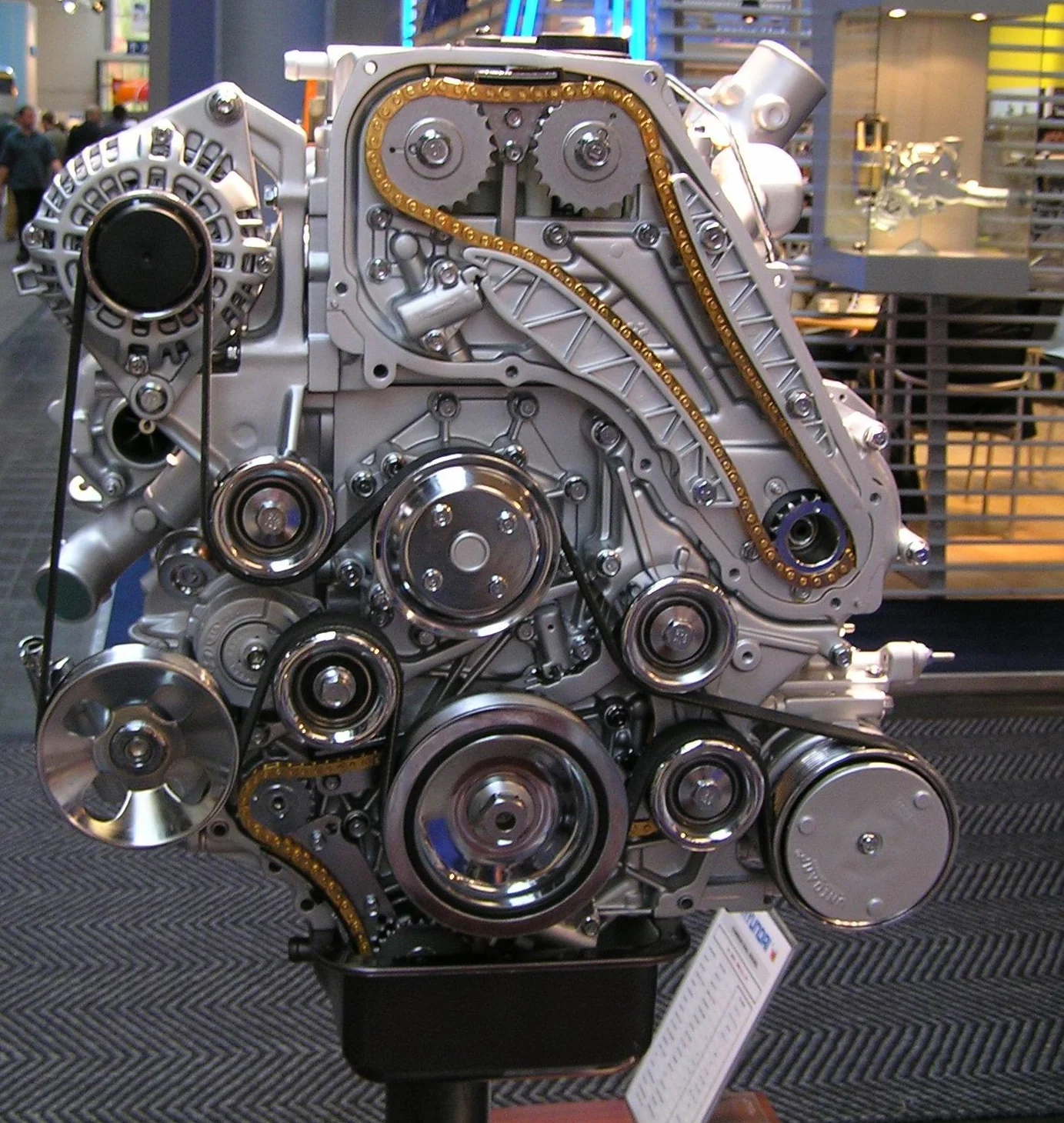 Hyundai engine on a stand, gold timing chain on the cam drive and a black serpentine on the accessories