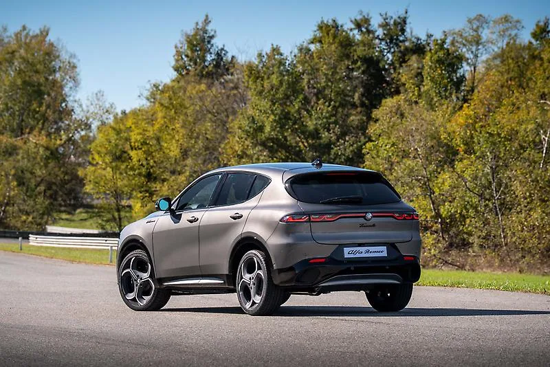 Gray 2026 Alfa Romeo Tonale Sport Speciale, rear three-quarter on a tree-lined road with a slim tail-lamp bar and Tonale script